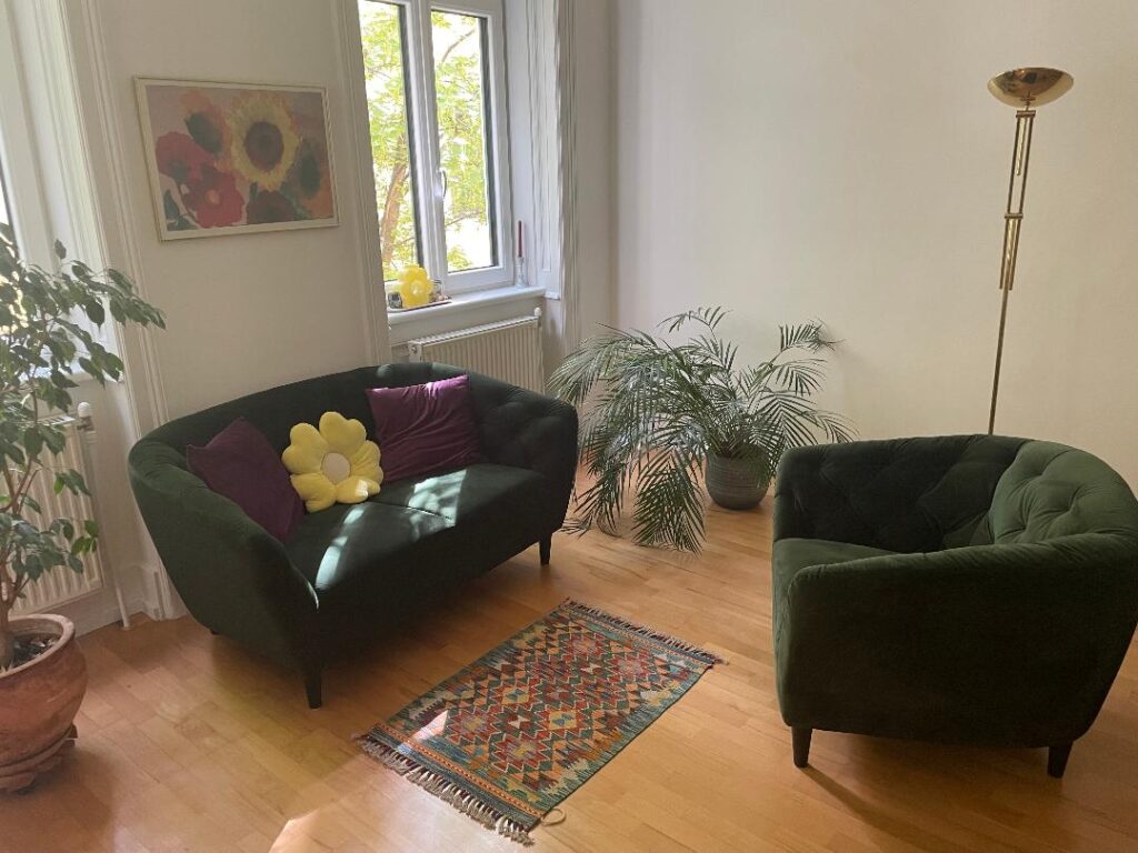 Sofa und Sessel vor Fenster mit Sonnenlicht.